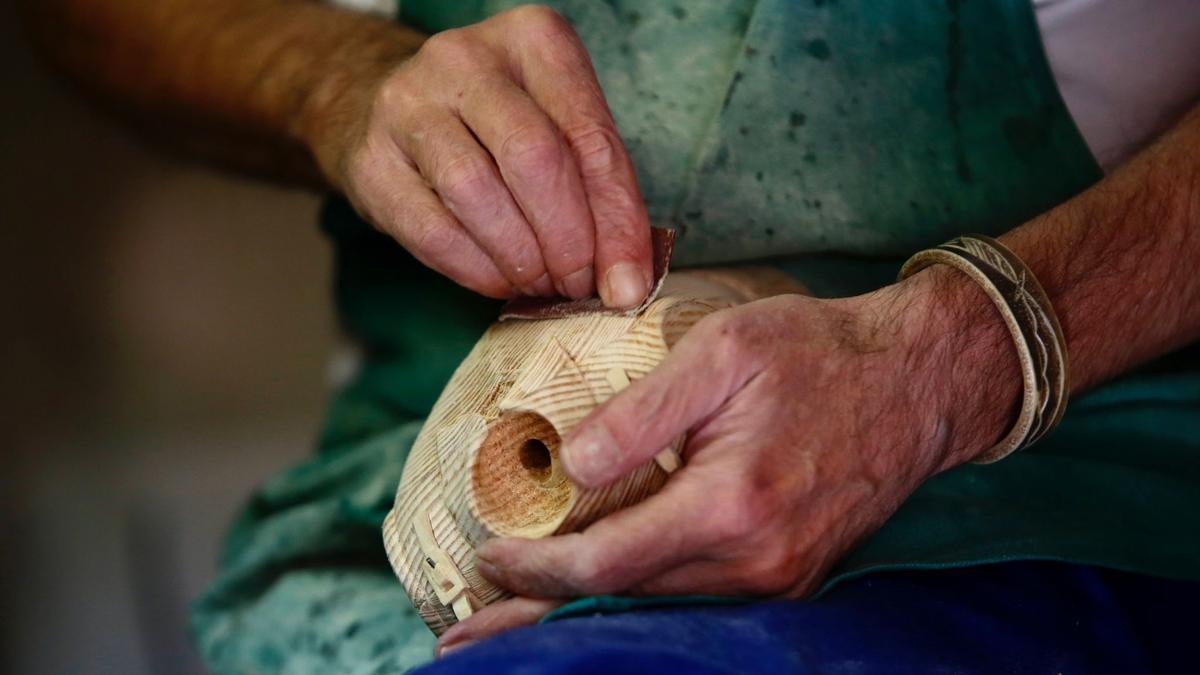 Las manos del escultor Ricardo Cane tallan el busto de una figura de madera