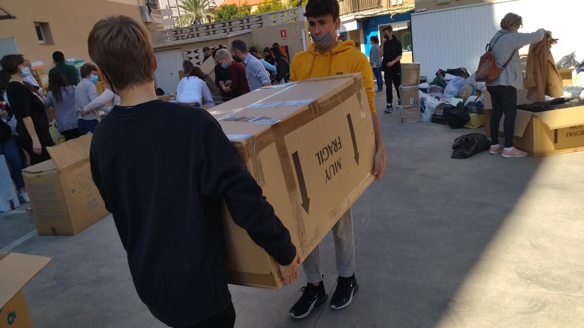 Dos alumnos cargan con una de las cajas de ayuda solidaria