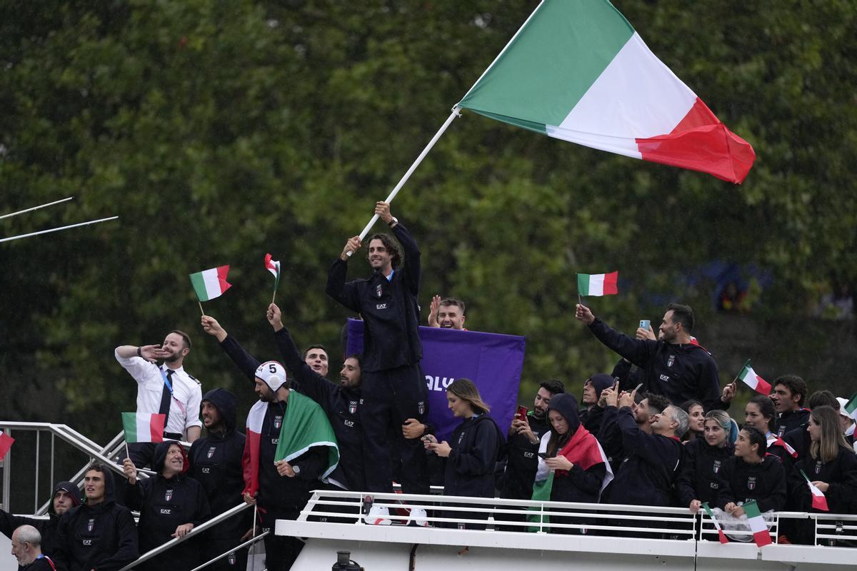 Gianmarco Tamberi ondea una bandera italiana mientras el equipo italiano desfila a lo largo del río Sena en París, Francia, durante la ceremonia de apertura de los Juegos Olímpicos