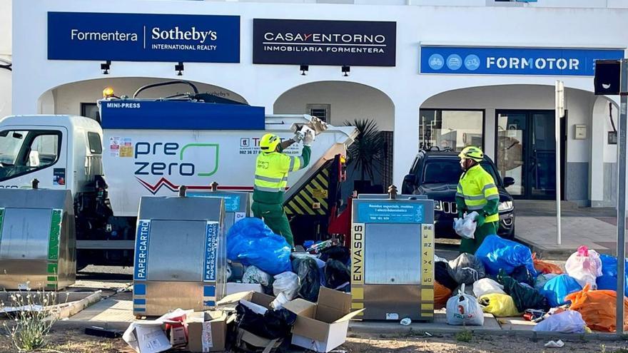 Dos trabajadores recogen la basura del entorno de unos contenedores soterrados en la Savina.