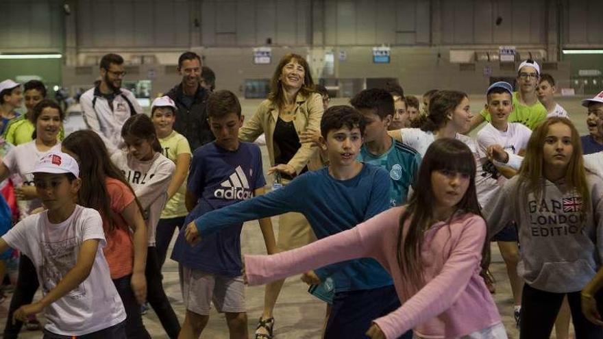 Arriba, un grupo de escolares, con Marta Miguel al fondo, se mueve al ritmo de un monitor. A la izquierda, una joven controla un balón. // Bernabé/Ana Agra