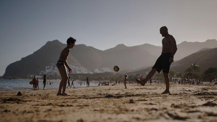 Un niño y un hombre juegan con una pelota en la playa de Las Teresitas