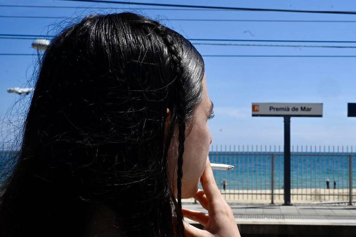 Una joven sujeta un cigarrillo frente a la estación de tren de Premià de Mar.