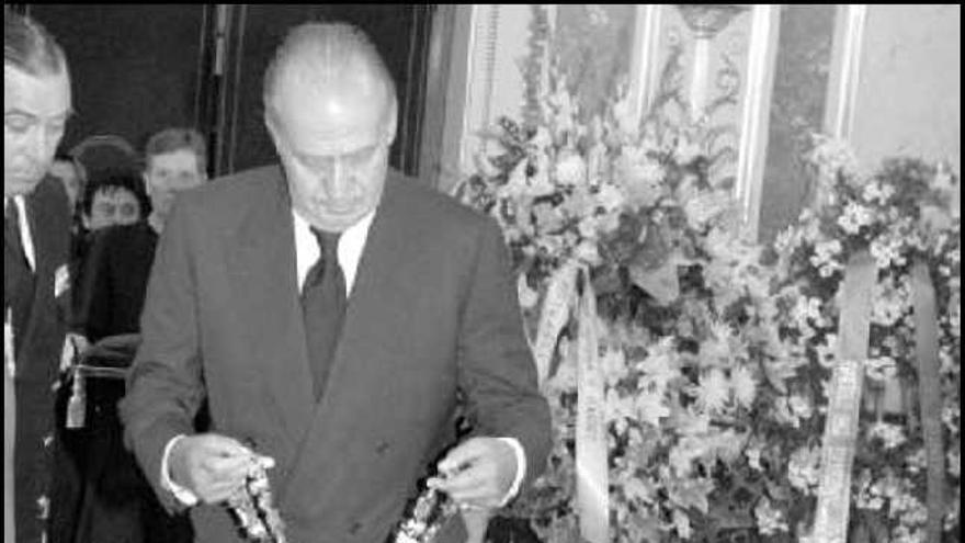 Don Juan Carlos deposita sobre el féretro el collar de la orden de Carlos III. El Rey se despide de un nieto de Calvo-Sotelo, en presencia de un hijo del finado.