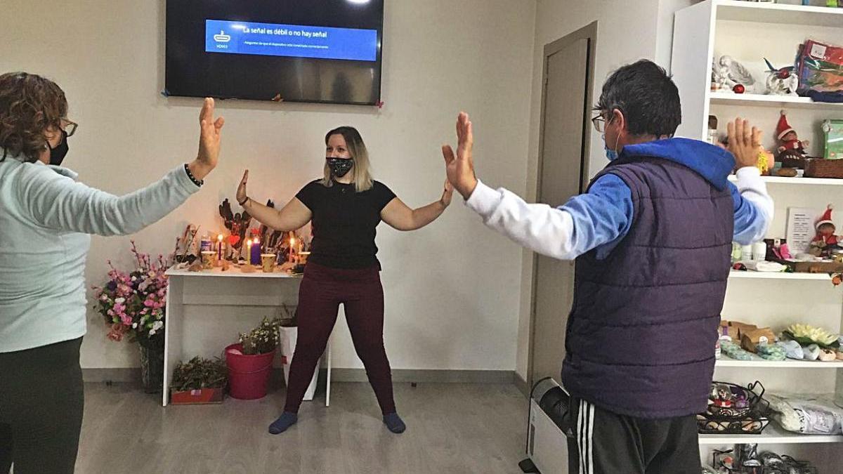 La profesora y dos alumnos, todos con                                mascarilla, en una clase.