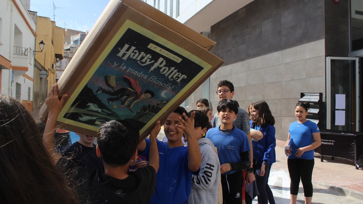 Un grupo de niños se pasa un ejemplar gigante de cartón de 'Harry Potter y la piedra filosofal'.