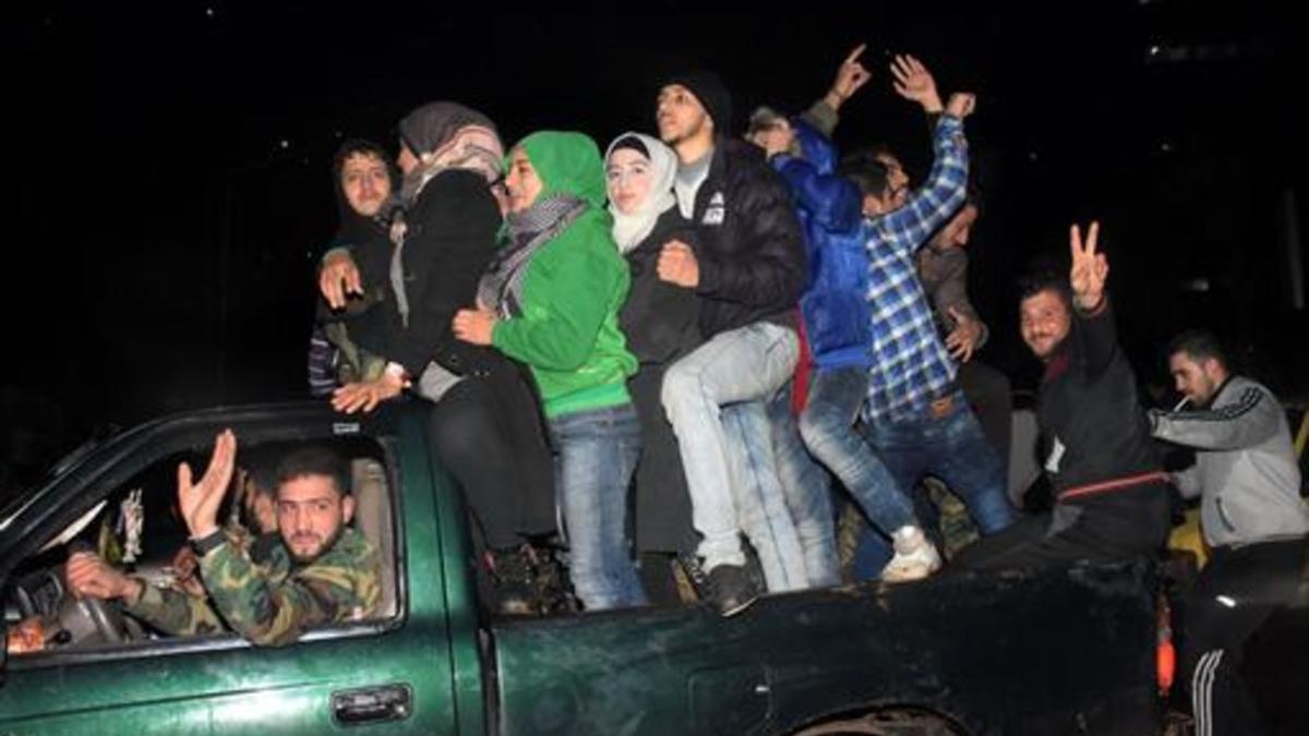 Un combatiente progubernamental carga a una mujer herida por un disparo rebelde cuando huía del barrio de Al Salhín, en Alepo.