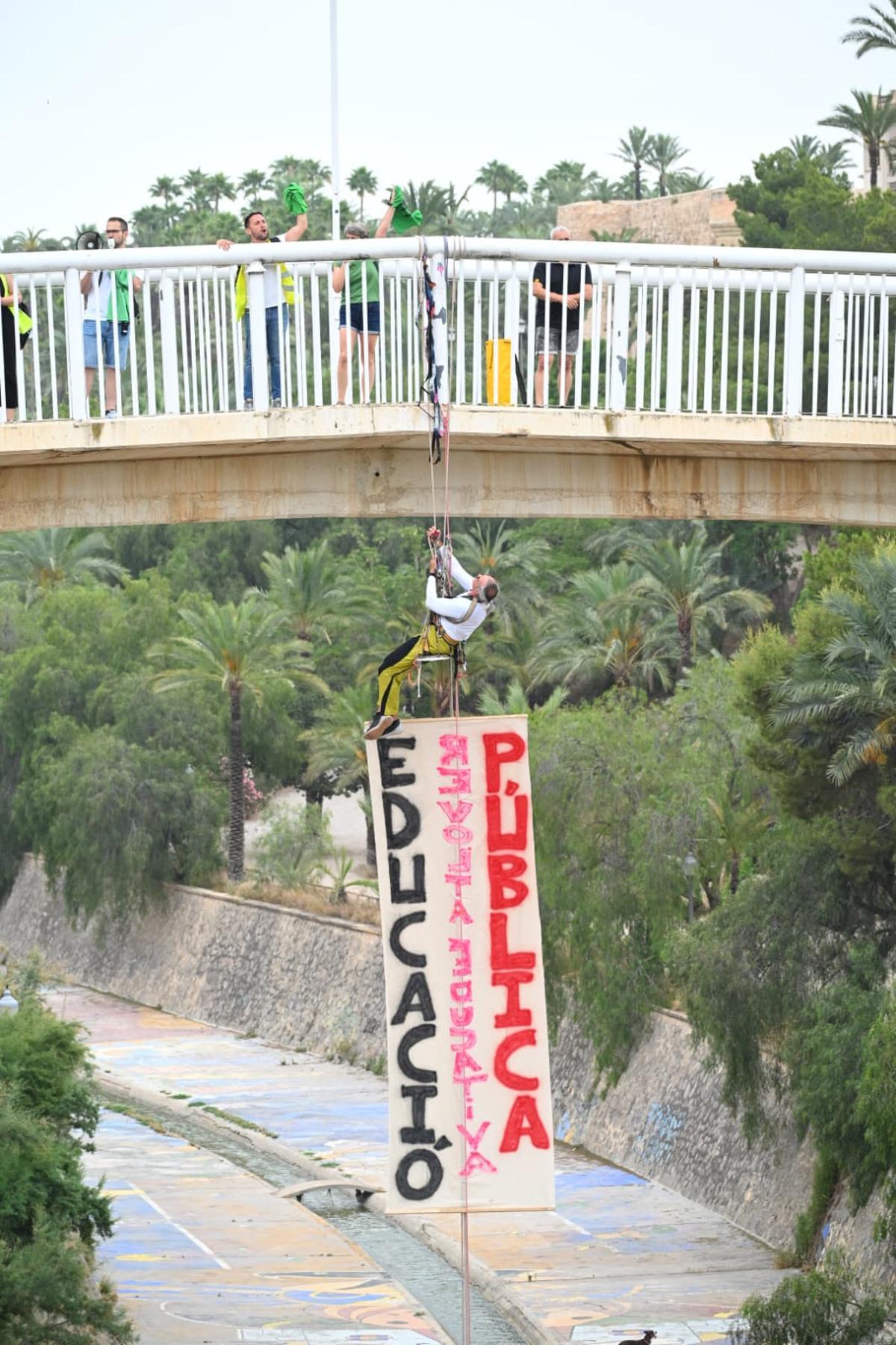 La huelga educativa escala en Elche: un profesor se cuelga de un puente con una pancarta