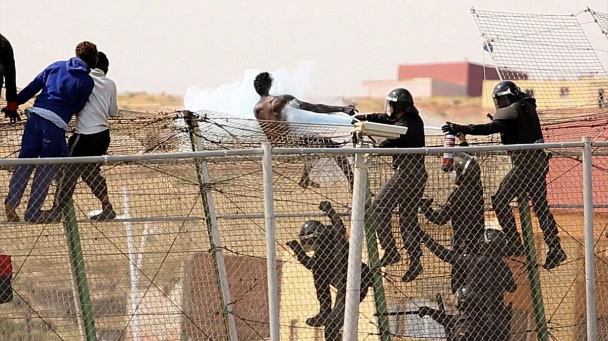 Guardias civiles rocían con un extintor a inmigrantes que intentaban usar mecheros en la valla de Melilla en una operación anterior.