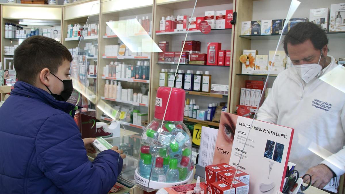 Un nen comprant un test d&#039;antígens en una farmàcia