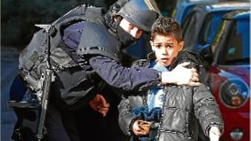 Un policia atura un nen que es dirigia a la zona conflictiva.