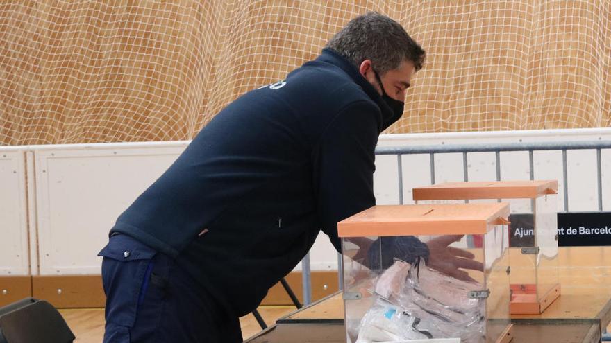 Un operari col·loca les urnes en una mesa electoral del poliesportiu Camp del Ferro de Barcelona. Imatge del 13 de febrer del 2021.