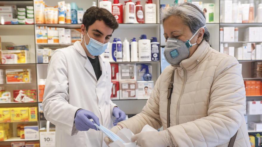 Una mujer compra mascarillas en una farmacia.