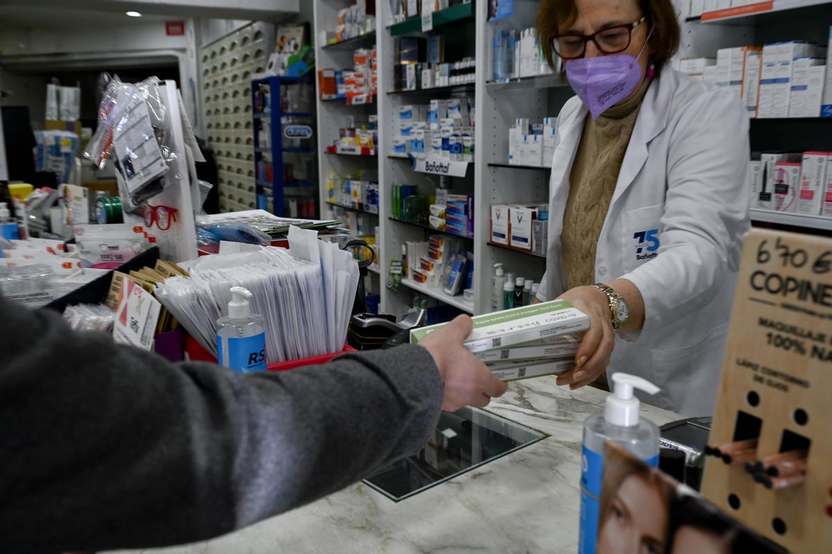 Una farmacéutica despacha tests de antígenos en su farmacia el 15 de enero de 2022, primer día con el precio máximo de 2,94 euros impuesto por el Gobierno.