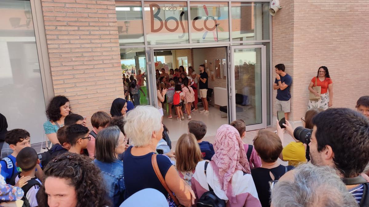Escolares entrando en el nuevo CEIP Bosco de Cocentaina, con otros alumnos y sus familias en la puerta, en medio de un ambiente eufórico.