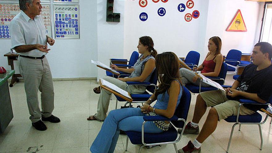 Cursos. Un profesor de autoescuela imparte una clase de conducir a un grupo de alumnos.