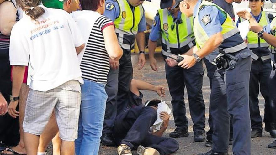 Un grupo de agentes de la Policía Local de Pájara rodean a un bombero tirado en el suelo.