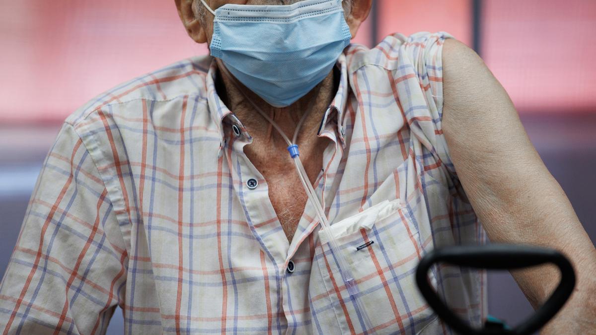 Un anciano prepara su brazo para la inyección de la dosis Moderna durante el inicio de la administración de la cuarta dosis de la vacuna frente al COVID-19 a los usuarios y trabajadores sociosanitarios de residencias.