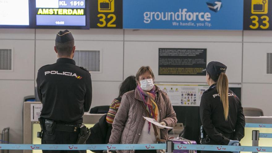 Dos policías supervisan la facturación de un vuelo para repatriar a turistas en el aeropuerto.