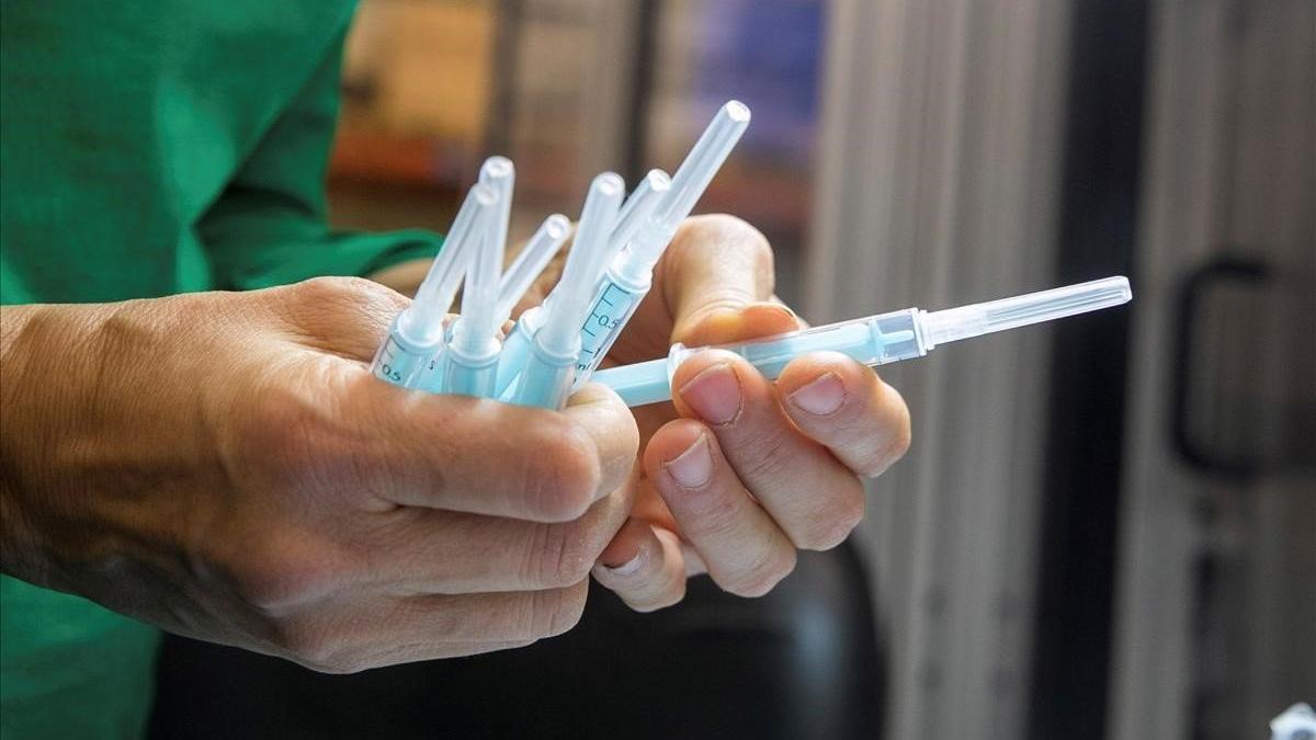 Una operaria inspecciona muestras de jeringuilla para la vacuna contra el coronavirus.