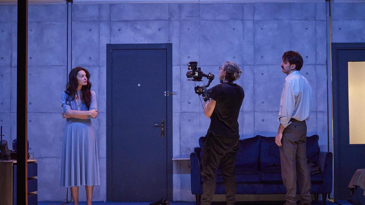 Una cámara filma en todo momento la obra teatral, ya que los primeros planos de los protagonistas se proyectan en blanco y negro en una gran pantalla sobre el escenario