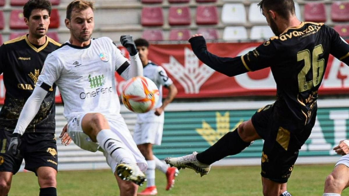 Jordan despeja el cuero en presencia de un jugador del Salamanca UDS CF.