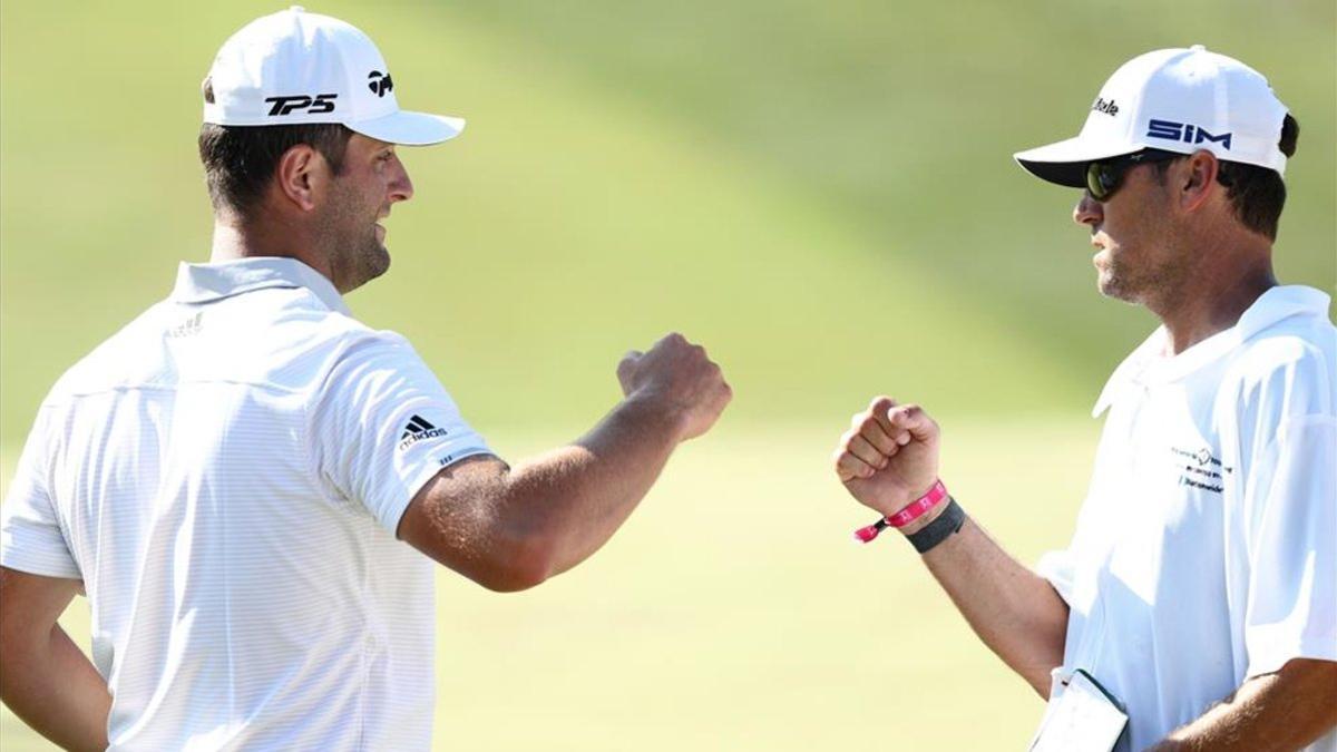 Jon Rahm y su caddie se felicitan en el hoyo 18