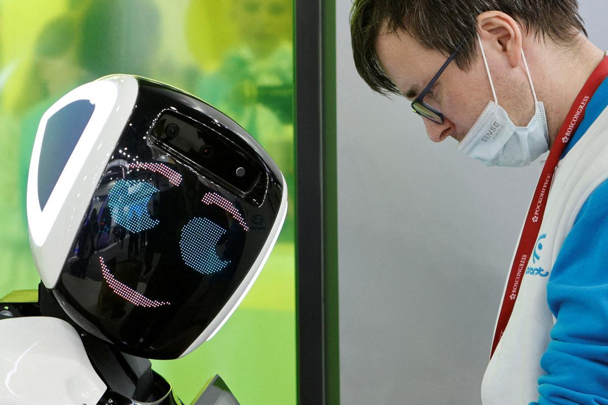 Un participantes del Foro Económico Internacional de San Petersburgo, junto a un robot.