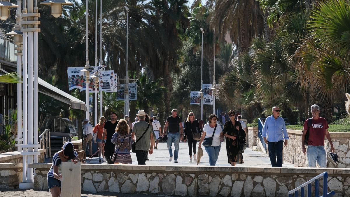 Numerosos ciudadanos pasean por un paseo marítimo en la capital malagueña.