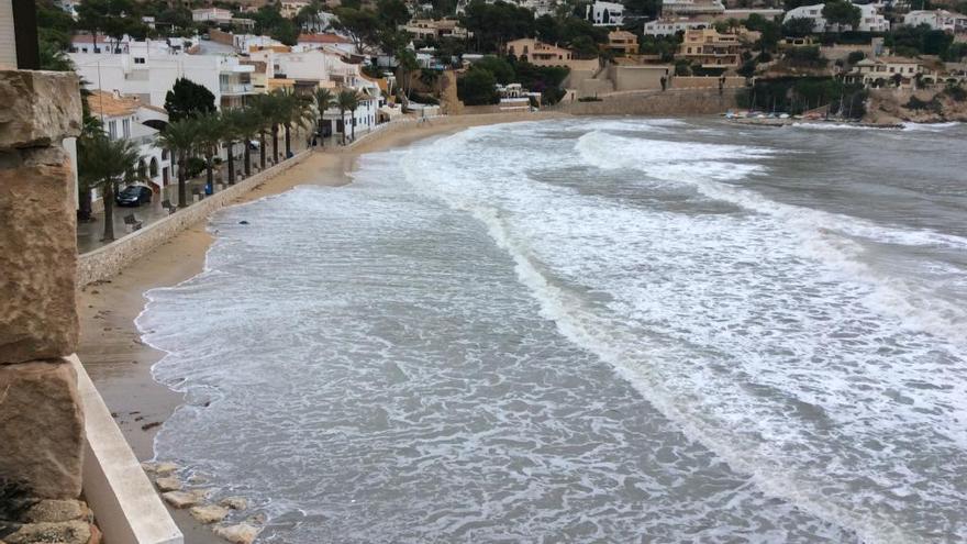 Las olas engullen la playa del Portet de Moraira y golpean el muro del paseo.