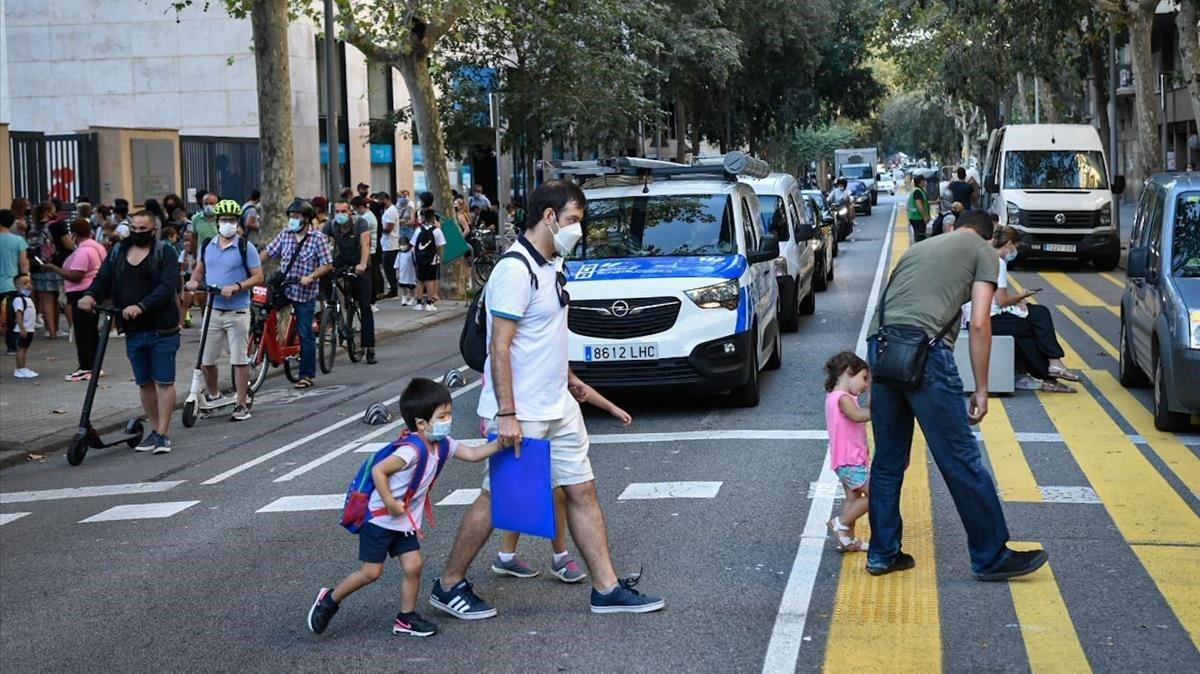 Padres llevando a sus hijos a la escuela en el primer día de clase.