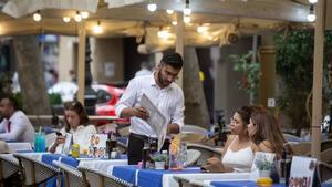 Un camarero atiende a dos clientas en una terraza en Barcelona.