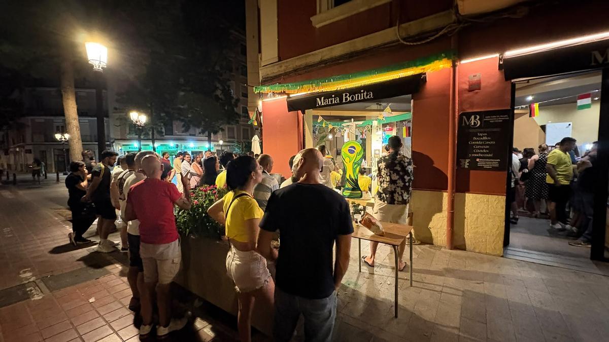 Aficionados en las puestas del local de Russafa viendo el Brasil-Marruecos