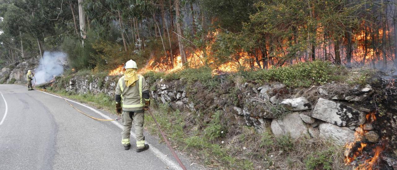 Bomberos trabajando en las labores de extinción del fuego que calcinó 50 hectáreas en Baredo.  // R. GROBAS