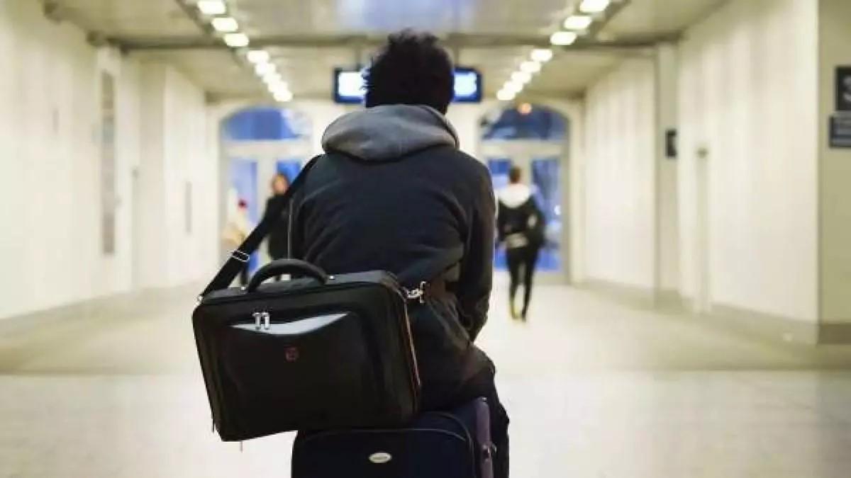Un joven se desplaza con sus maletas por una estación de tren.