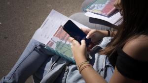 Una estudiante consulta su móvil, en las inmediaciones de un instituto de Barcelona.