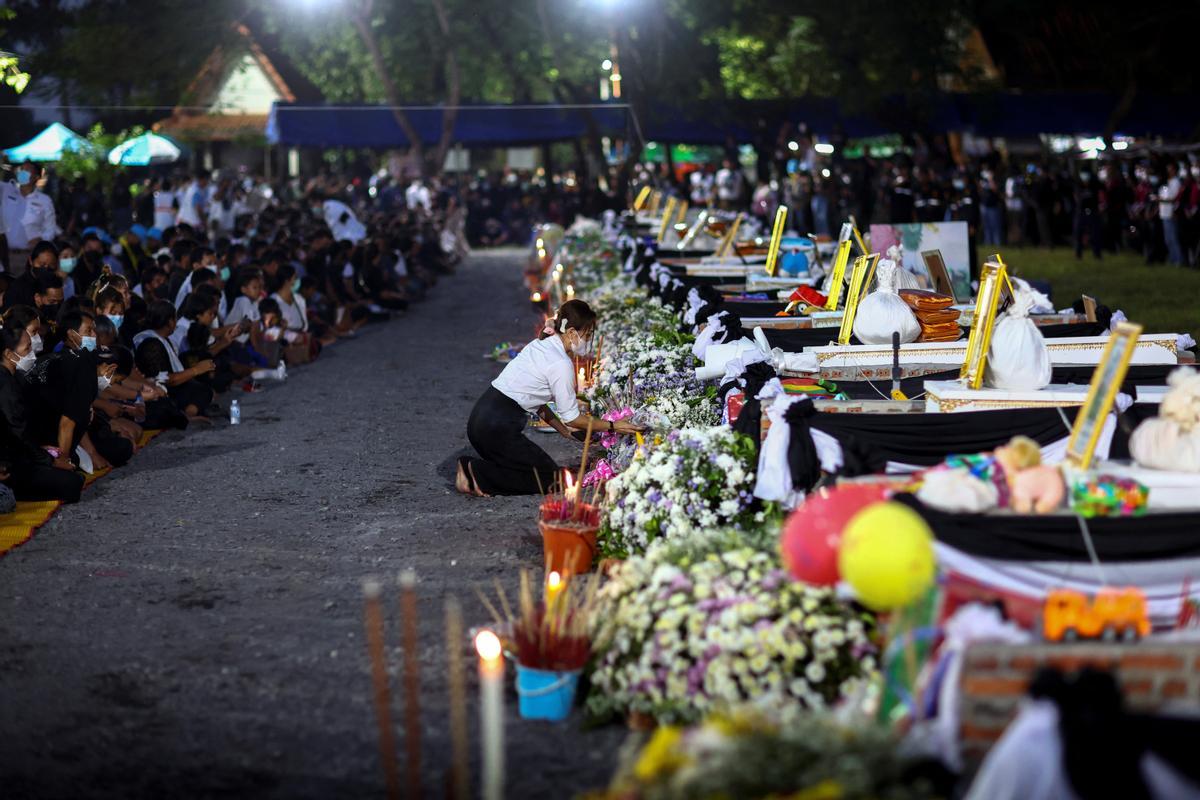 Una persona rinde homenaje ante los féretros de las víctimas, el día de una cremación en el templo Wat Rat Samakee.