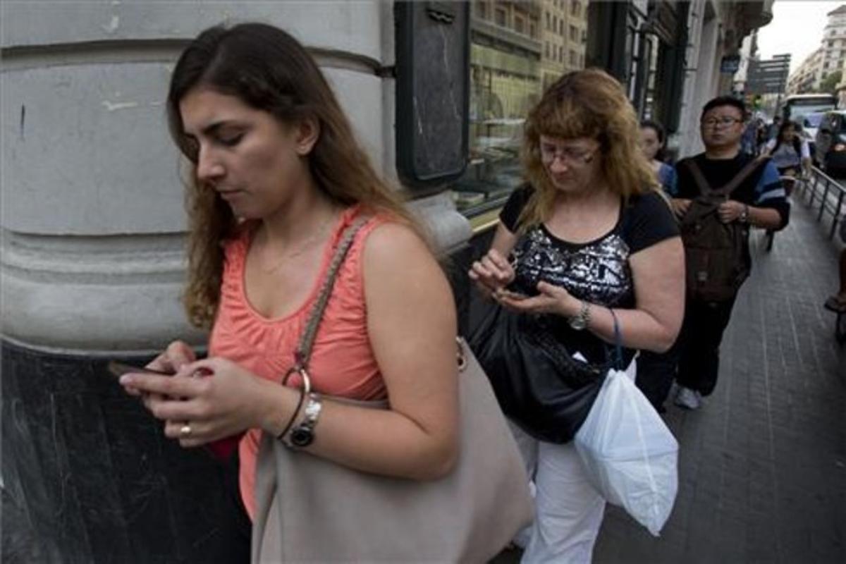 Usuarios de ’smartphones’ chateando mientras caminan. Usuarios de ’smartphones’ chateando mientras caminan.
