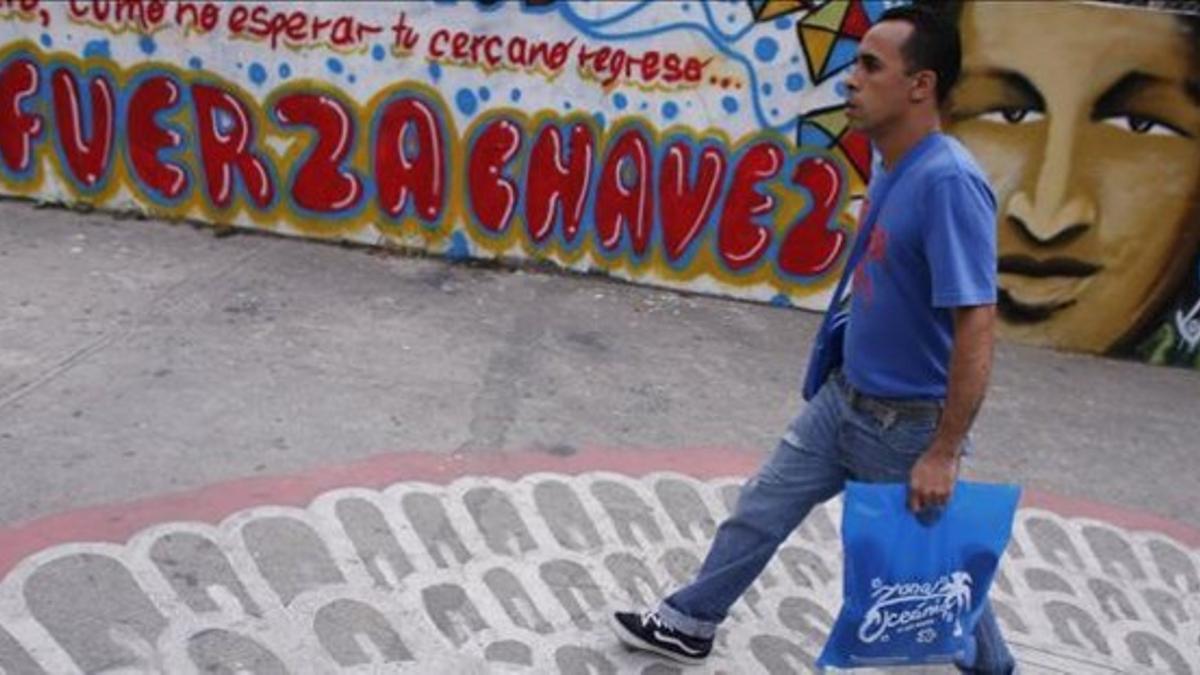 Un hombre pasa por delante de una pintada favorable a Chávez, este lunes en Caracas.