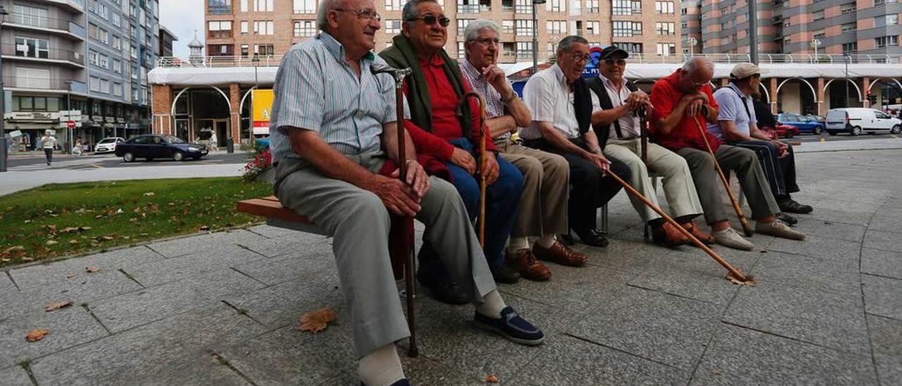 Jubilados sentados en un banco del parque de Las Meanas de Avilés.