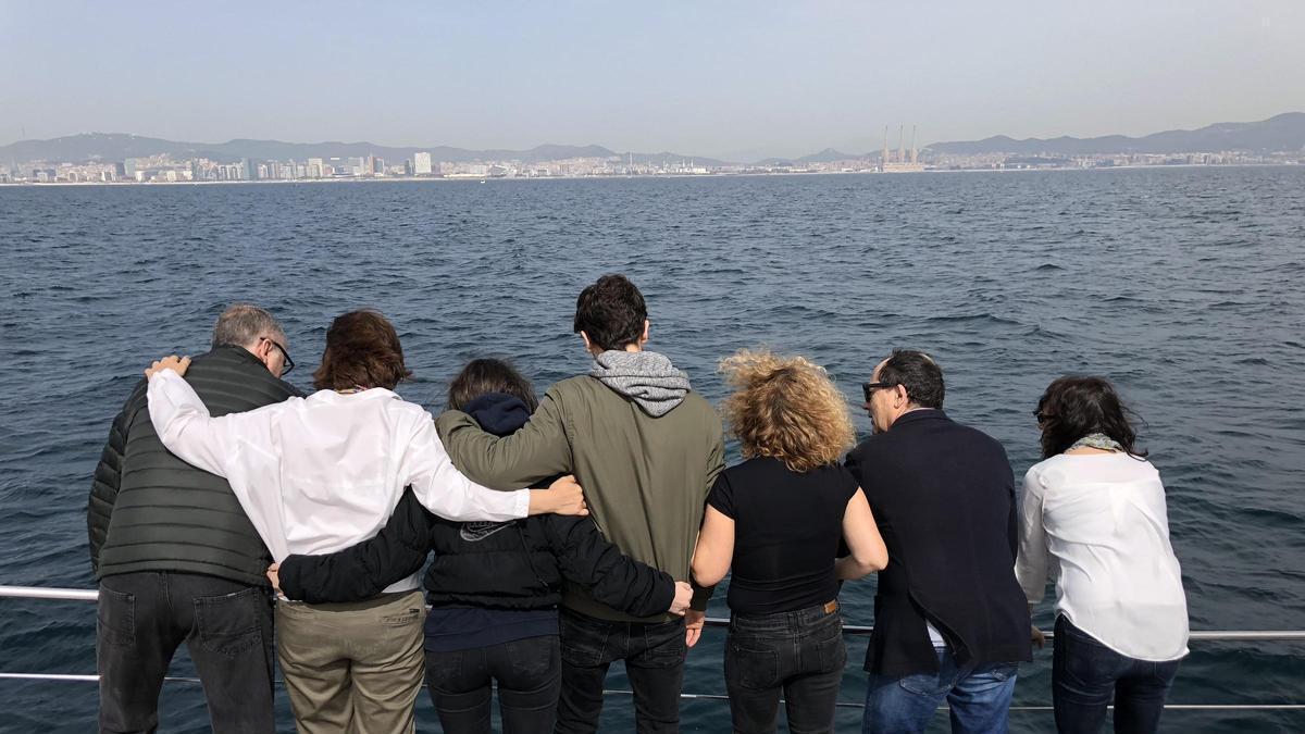 Una familia abrazada druante un vertido de cenizas al Mar Mediterráneo.