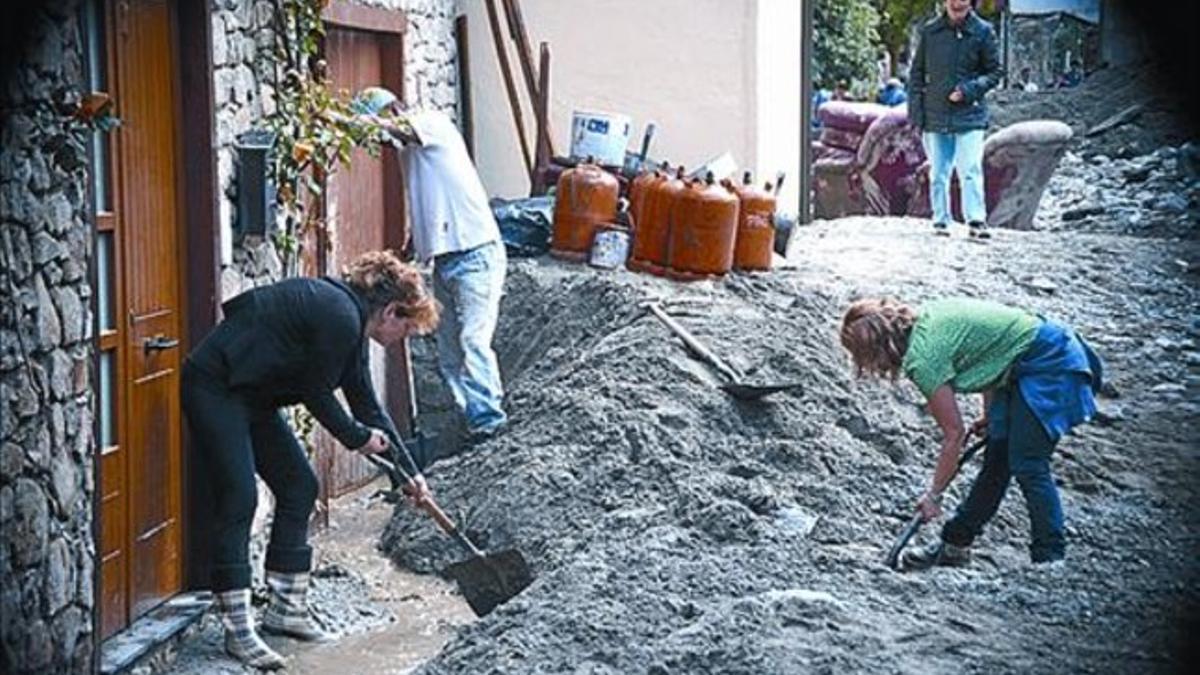 Unos vecinos retiran lodo en una calle.