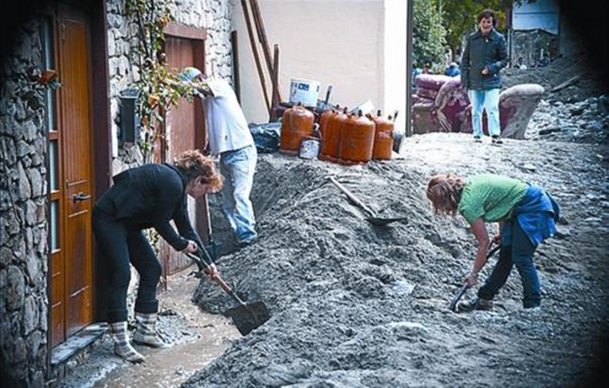 Uns veïns retiren fang en un carrer d’Arties, dimecres.