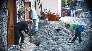 Uns veïns retiren fang en un carrer d’Arties, dimecres.