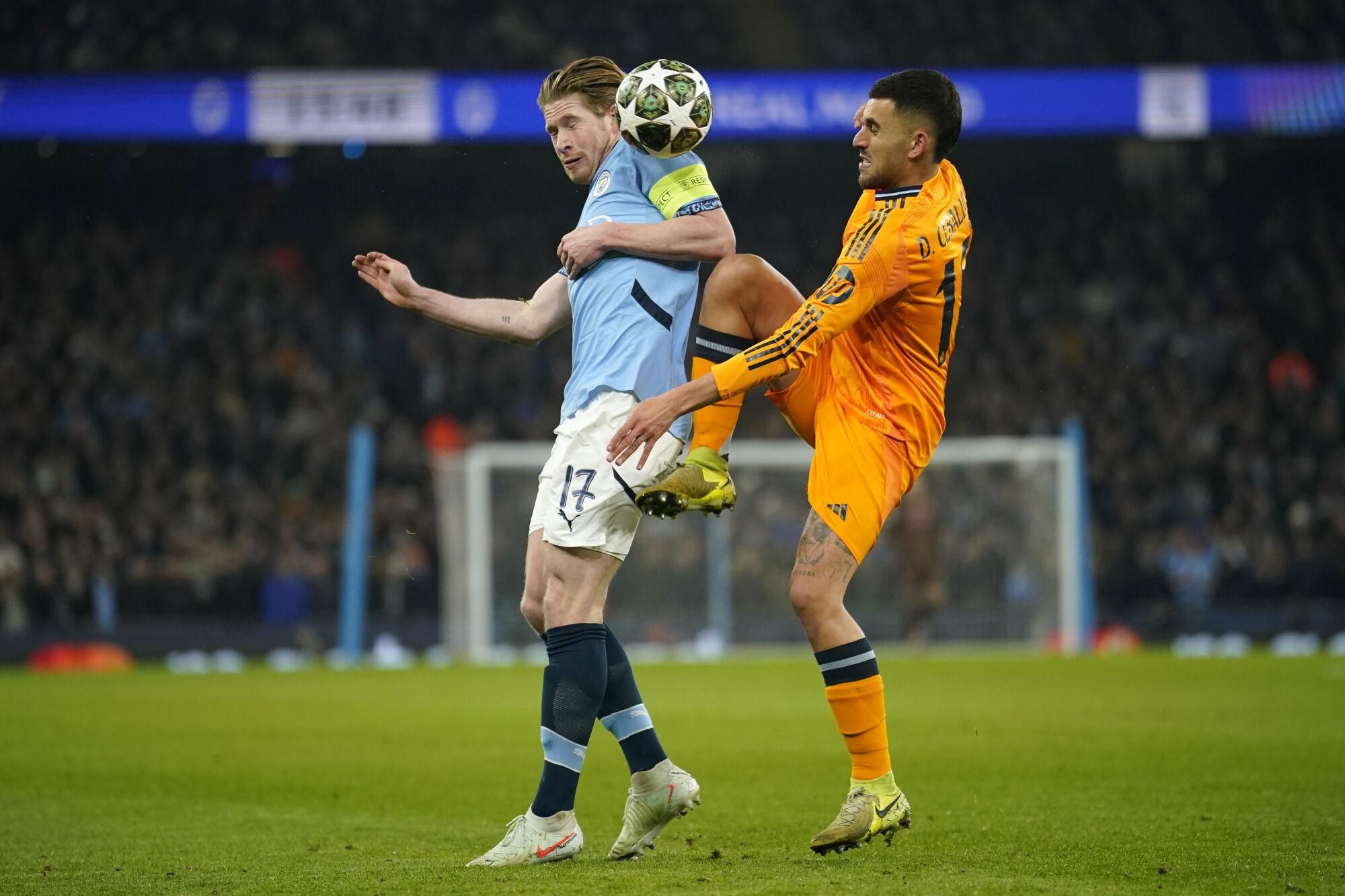 Real Madrid's Dani Ceballos, right, challenges Manchester City's Kevin De Bruyne during the Champions League playoff first leg soccer match between Manchester City and Real Madrid at the Etihad Stadium in Manchester, England, Tuesday, Feb. 11, 2025. (AP Photo/Dave Thompson)