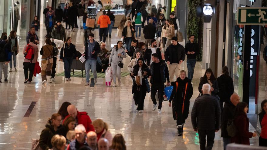 Filas en los accesos a distintas tiendas de la planta calle del centro comercial de Puerto Venecia de Zaragoza.