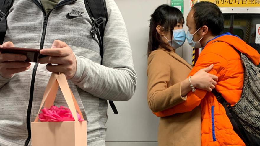 Una pareja con mascarillas se abraza en un tren.