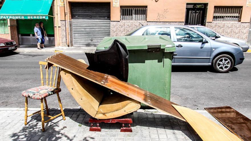 Muebles abandonados en un contenedor de basura de Elda