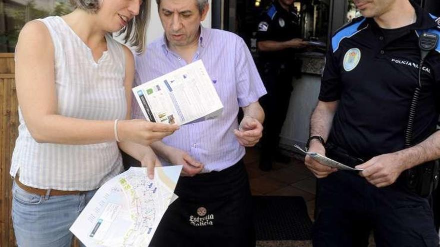 María García y un policía muestran la información a un hostelero.