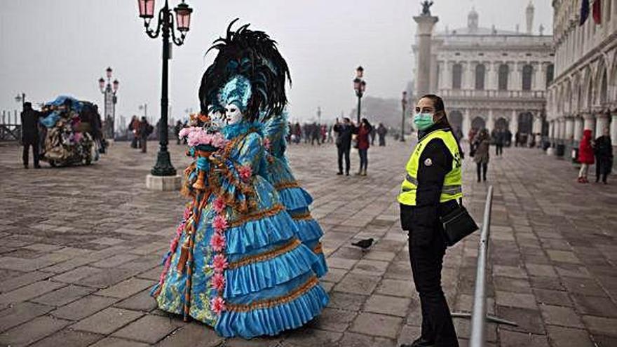 Una policía con mascarilla junto a una persona disfrazada en Venecia.